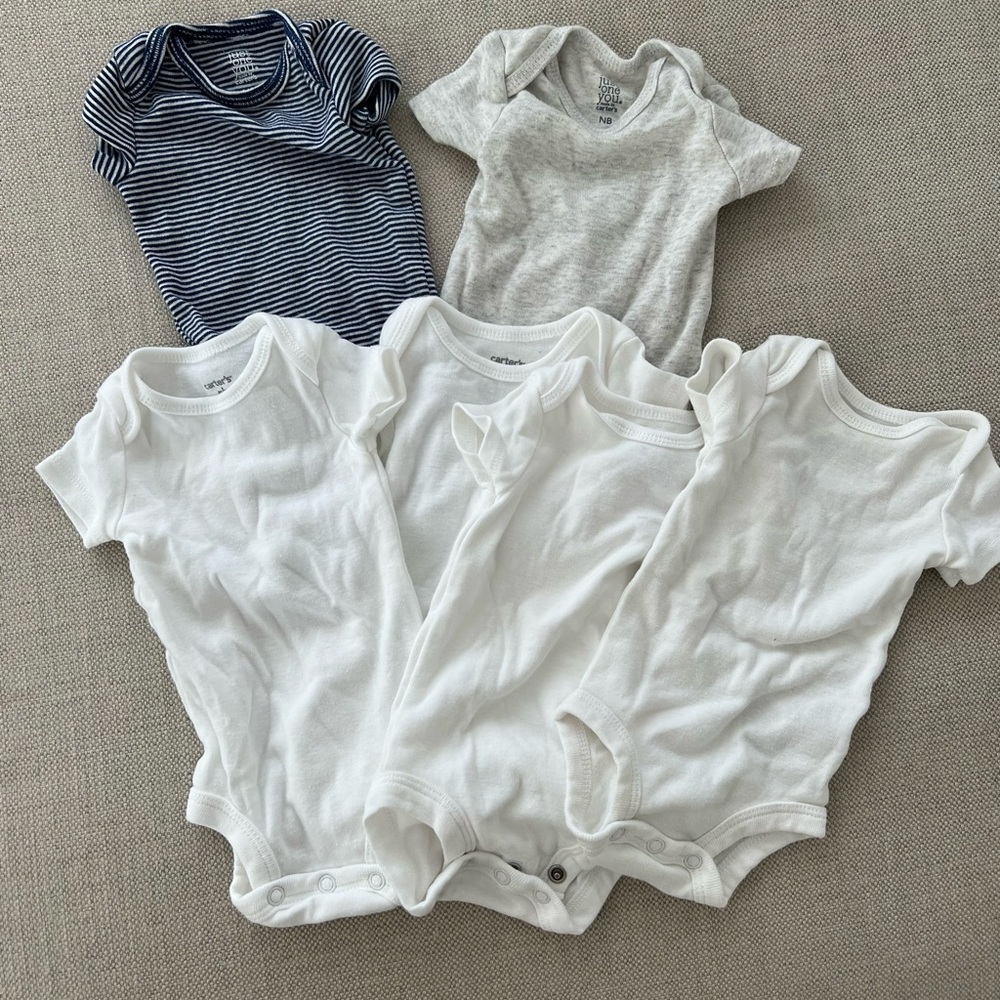 Carter’s lot of newborn onesies in white, navy stripe and solid grey.